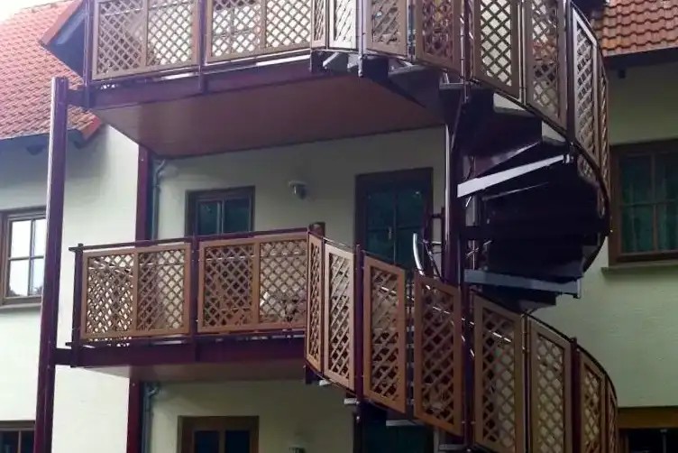 Wendeltreppe aus Metall mit Balkonen und Gitterfüllung an einem Wohnhaus